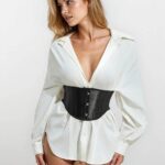 Kvinna bär vit skjorta och svart korsett. Kort midjekorsett